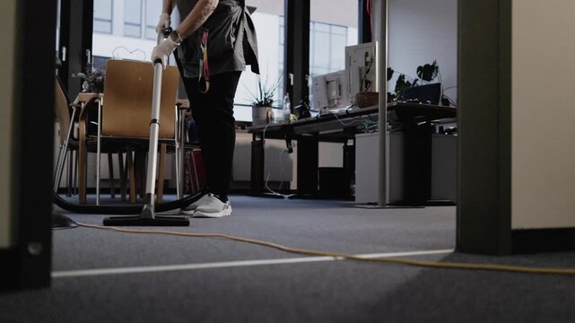 Reinigungskraft saugt den B&uuml;roteppich