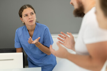 Fototapeta premium Dental clinic administrator talks to patients at the reception desk
