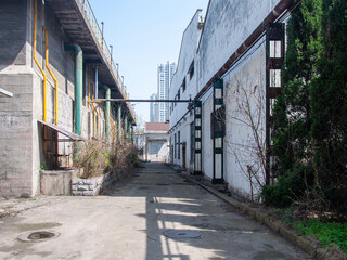 Obraz premium Narrow Industrial Alleyway with Yellow Overhead Pipes