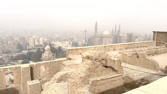 Elevated view of historic stone ruins overlooking the Cairo cityscape in Cairo, Egypt. Traditional architecture in the foreground with mosques and urban skyline in the Cairo.