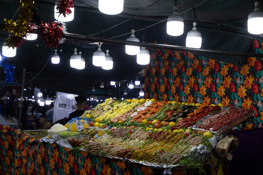 Food stall at night, brightly lit with various meats, vegetables, and skewers on display. Jamaa el Fna,Marrakech,Unesco hertage,Morocco