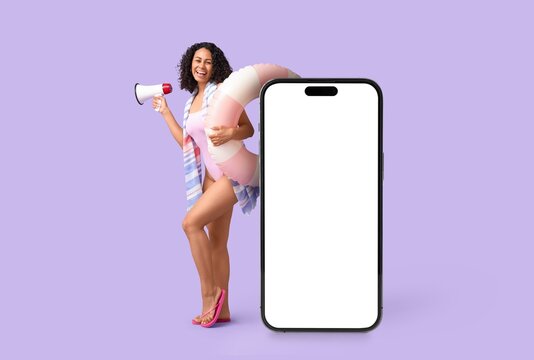 Young African-American woman with swimming ring, megaphone and big mobile phone on lilac background. Banner for design