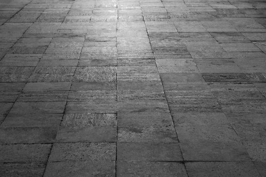 Sunlit weathered stone floor with aged texture Perspective of paving slabs in grey gray light background with pavement tiles in silver beige sunlight. shiny sidewalk. sunny backdrop of urban footpath.
