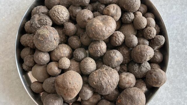 Harvested air potatoes (Dioscorea bulbifera) piled in a round metal tray