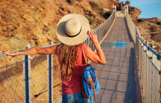 Carefree woman walks on suspension bridge. Torrenueva, Granada province in Spain. tourism, travel, vacation