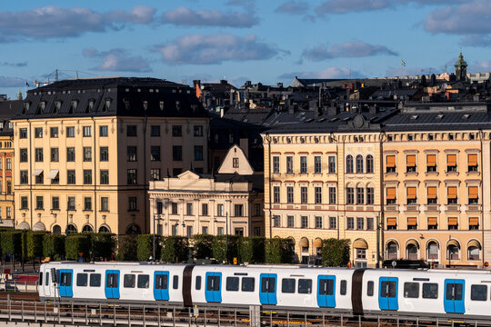 Urban waterfront view with a metro train passing the city skyline and buildings in Stockholm Sweden capturing transportation and calm blue water