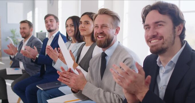 Business team audience applauds during corporate training. Applause marks the end of a seminar meeting and a short presentation in room. Clear concept: teamwork recognition and motivation.