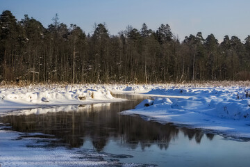 A snow-covered sunny landscape with winding river and trees