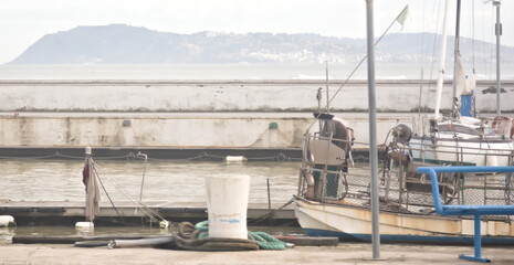 Barca a vela ormeggiata al molo con attrezzature nautiche e vista su montagna oltre l&rsquo;acqua
