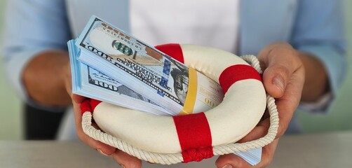 A person holding a life ring full of cash, symbolizing financial security