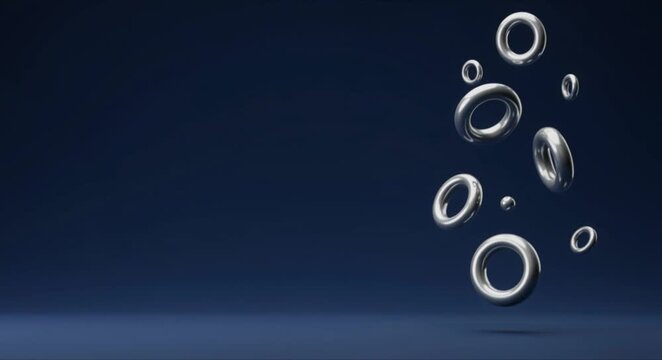 Cinematic seamless loop of 3d floating silver rings on right with solid minimalist navy blue copy space and professional lighting