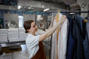 A woman worker hangs freshly washed clothes on a rack in a laundromat