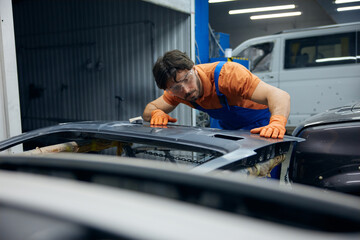 Technician worker skillfully restoring a car door in a busy garage workshop space