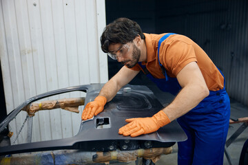 An technician skillfully restoring a car door in a busy garage workshop space