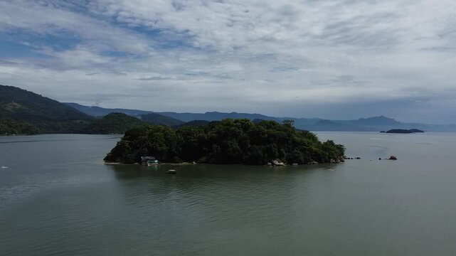 Drone circling around a tropical island, Ilha dos Pombos near Paraty, Brazil, showing a small tropical island in context with Scenic nature and ocean landscape.