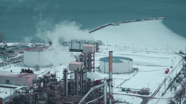 Aerial view of snow-covered refinery near lake in Canada, showing climate impact