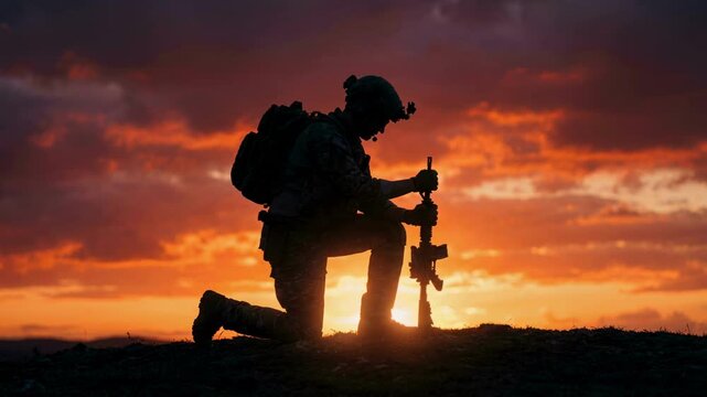 Silhouette of a military soldier kneeling with a rifle against a dramatic sunset sky. Army veteran praying or resting on a hill during a mission. War tribute and patriotism concept
