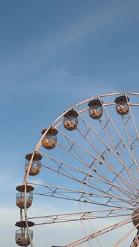 Ferris wheel cabins against blue sky form strong visual asset for tourism marketing and urban leisure branding, showing ferris wheel as recognizable travel symbol for city promotion and entertainment 