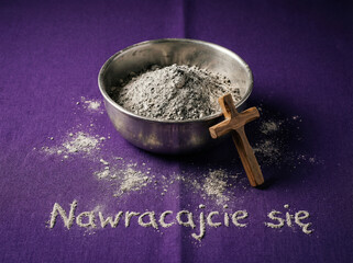 Fioletowe tło z popiołem w metalowej, srebrnej miseczce i małym drewnianym krzyżem. Obok napis "Nawracajcie się". Środa Popielcowa © Monika