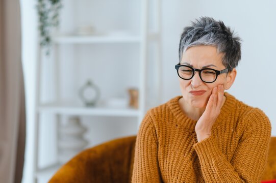Senior woman having toothache problem holding her cheek