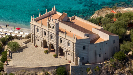 Aerial closeup of the Sanctuary of Santa Maria dell'Isola in Tropea, Calabria, Italy. The ancient church stands on a rocky promontory, overlooking the Mediterranean sea. It is a sunny summer morning. © Stefano Tammaro