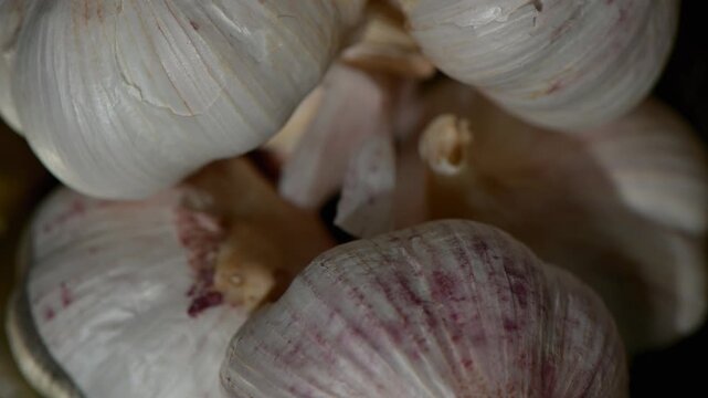 Elegant slow-motion rotation of a single whole garlic bulb against a clean white background. High-resolution 4K macro shot capturing the delicate papery skin, natural texture, and subtle shadows. Perf