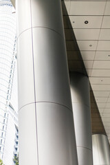 Obraz premium A set of large gray columns support the roof of a walkway in a city environment. The structure features smooth lines and contemporary materials, blending into modern architecture