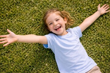 Little Girl Lying on Grass with Arms Open Laughing