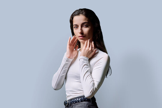 Portrait of beautiful fashionable young woman 18, 19 years old on gray background