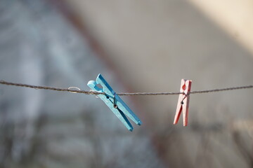 Stare, kolorowe klamerki przypięte do linki na świeżym powietrzu bez rozwieszonego prania. Prosta, codzienna scena z widoczną fakturą plastiku i śladami użytkowania.
