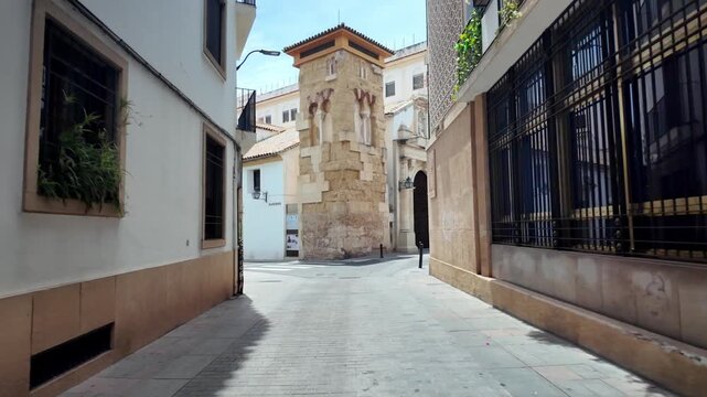Bright summer day view of a person entering the tranquil Jardines de la Merced public park entrance in historic C&oacute;rdoba, Andalusia, Spain.