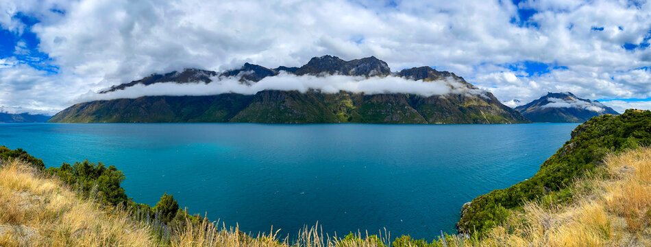 Panoramic view of Lake Wakatipu with mountain range and dramatic clouds, New Zealand