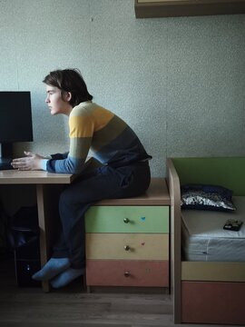 A teenager is sitting in profile on a pedestal,  student listening to educational podcast or e-learning via smartphone at home . Neurodiversity. Mental Health and Digital Balance. Mindfulness