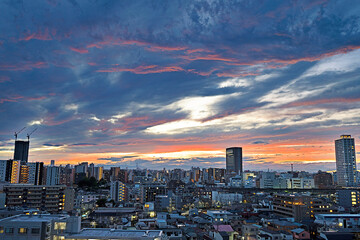 雲の隙間から見える夕焼けとビル群