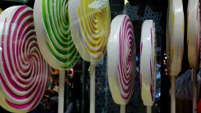 Rows of large colorful spiral lollipops with pink, green, yellow, and purple stripes on display.