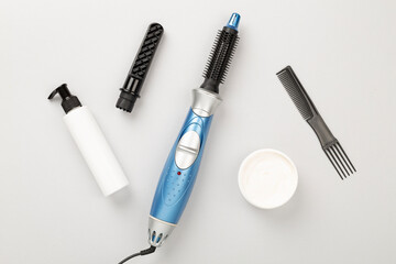 Hair styler with care products on color background, top view