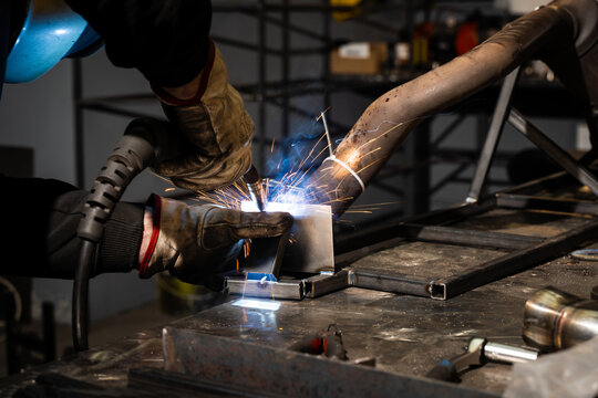 Worker welds steel with shielded arc using flux-coated electrode