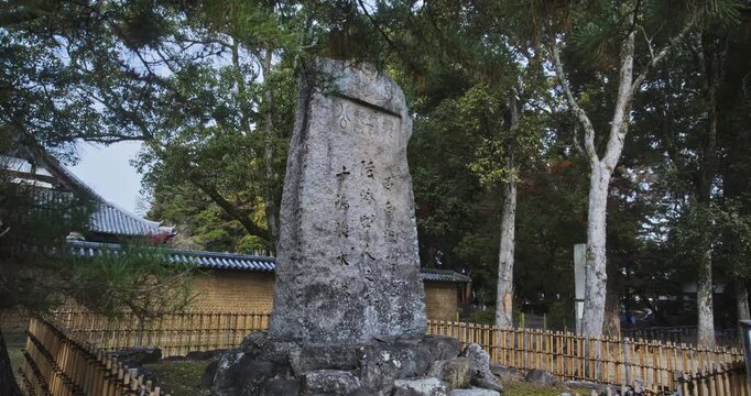 Slow, steady cam in on tall and ancient stone with Japanese text - medium shot
