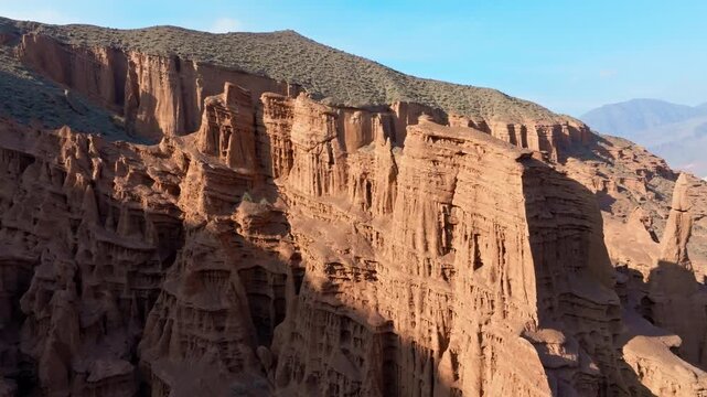 Aerial view captures vast natural rock formations in Konorchek canyons in Kyrgyzstan. Majestic landscape showcases stunning geological features under bright daylight.