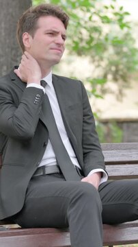 Young Businessman Sitting Outdoor with Neck Pain, Vertical Video