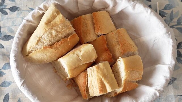 A basket of bread with a white cloth underneath it. The bread is cut into small pieces and arranged in a way that they look like a bunch of flowers