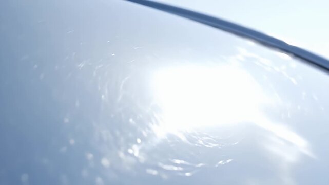 Bright sun glare on a smooth, reflective surface creating abstract patterns