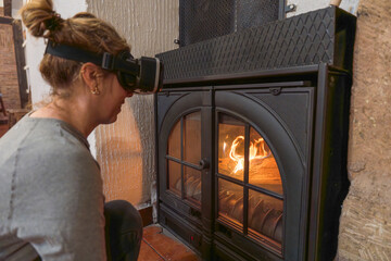 Woman wearing vr headset by warming fireplace