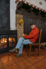 Man reading book by warm rustic fireplace