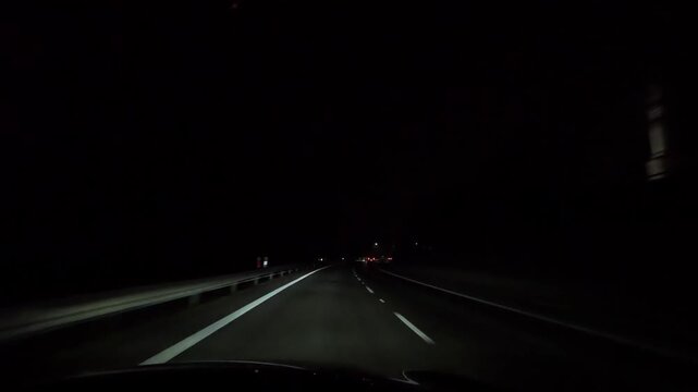 Night highway drive on multi lane road outside city illuminated by car headlights