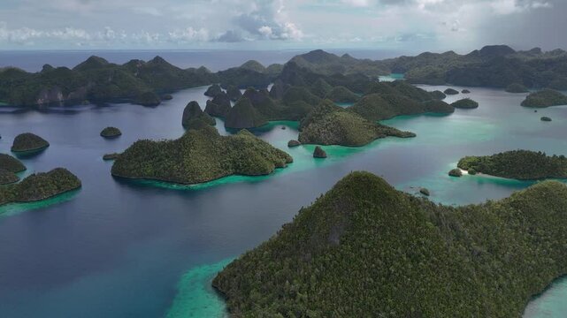 Aerial drone footage moving forward over the iconic limestone karst islands of Wayag, Raja Ampat, Indonesia. Stunning panoramic view of turquoise lagoons, emerald waters, and dramatic tropical island 