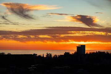 A stunning sunset over the sea with a bright orange sky and a hotel complex on the shore. The image showcases resort properties, perfect for travel and vacation-related themes. © NastyaPhoto