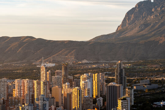 Golden sunset over skyline apartments and highrise towers in urban Benidorm Spain sets a panorama with mountains behind the coastal city