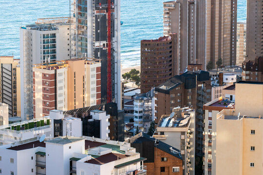 Sunlight on apartments and highrise buildings brings urban density to Benidorm Spain with coastal sea horizon and waterfront city living