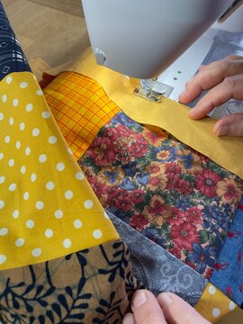 Many colorful square cotton fabrics are sewn together at the sewing machine to a patchwork and quilt blanket